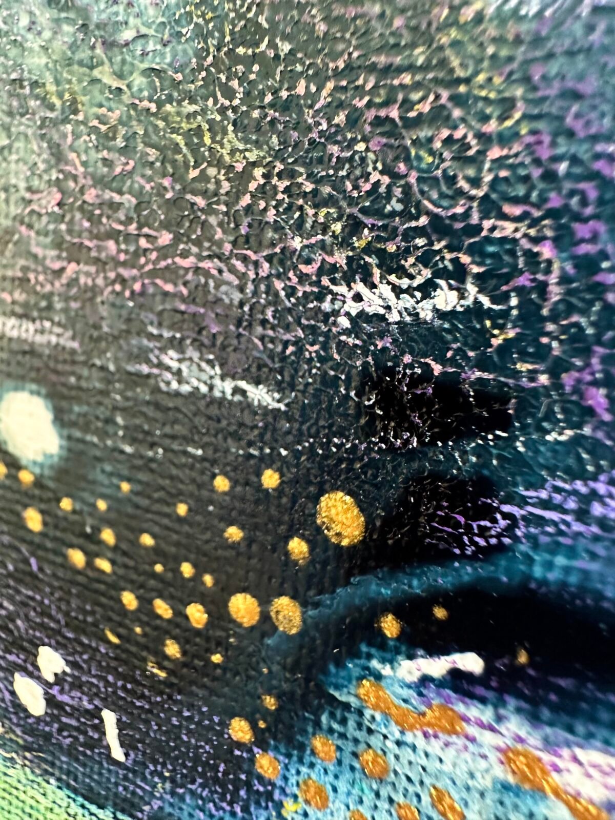 Close-up of dark textured paint with purple marks and metallic gold dots