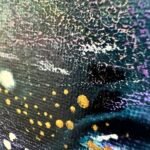 Close-up of dark textured paint with purple marks and metallic gold dots