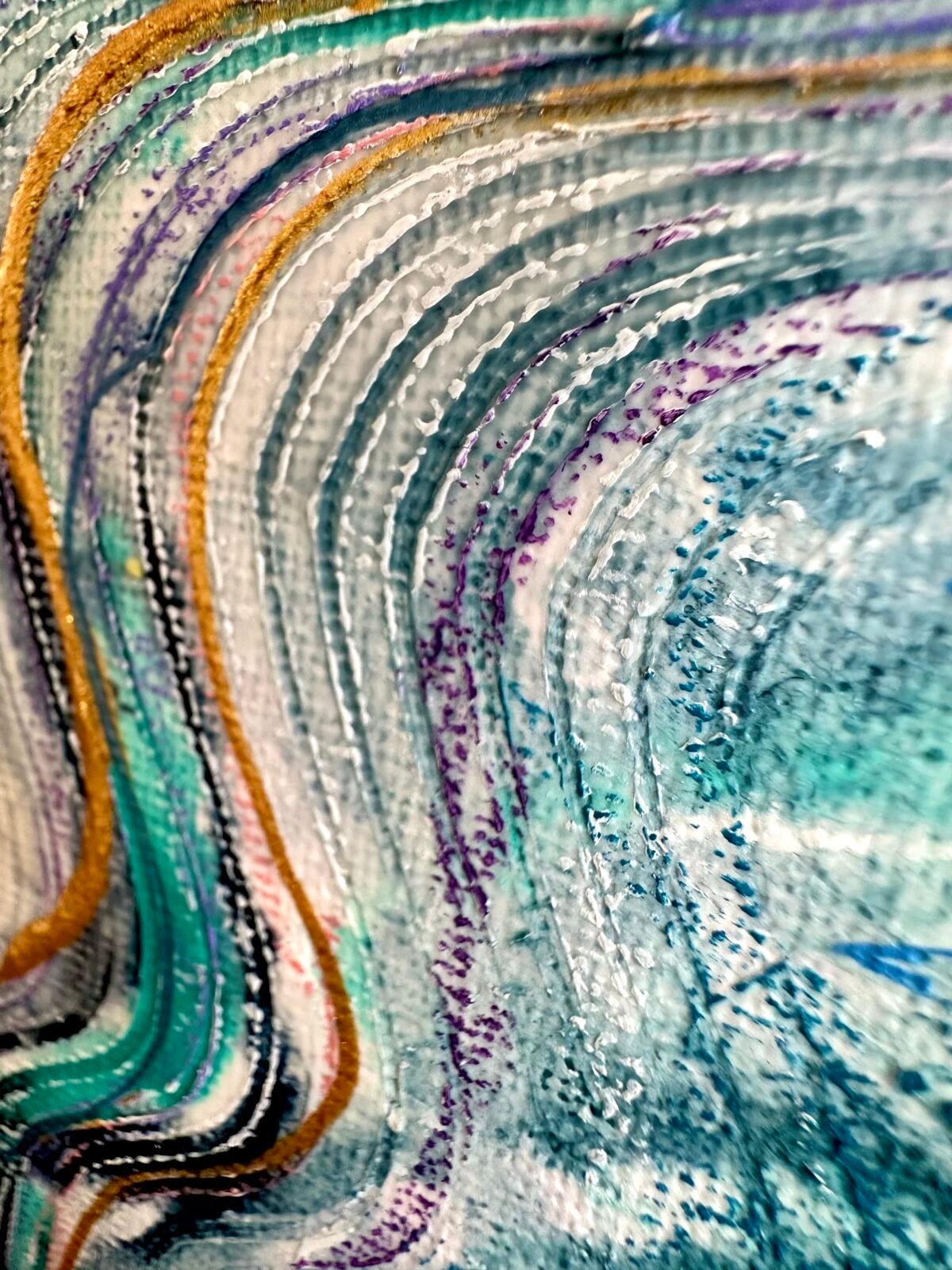 Close-up of flowing teal, white and gold painted lines on textured canvas