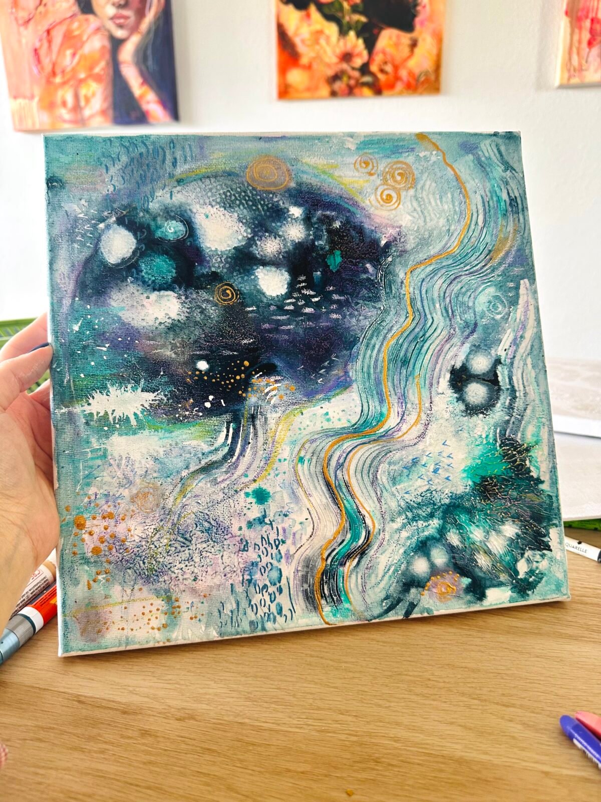 Blue, turquoise and gold abstract painting made with texture paste and acrylic inks, held in the artist’s Berlin studio.