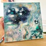 Blue, turquoise and gold abstract painting made with texture paste and acrylic inks, held in the artist’s Berlin studio.